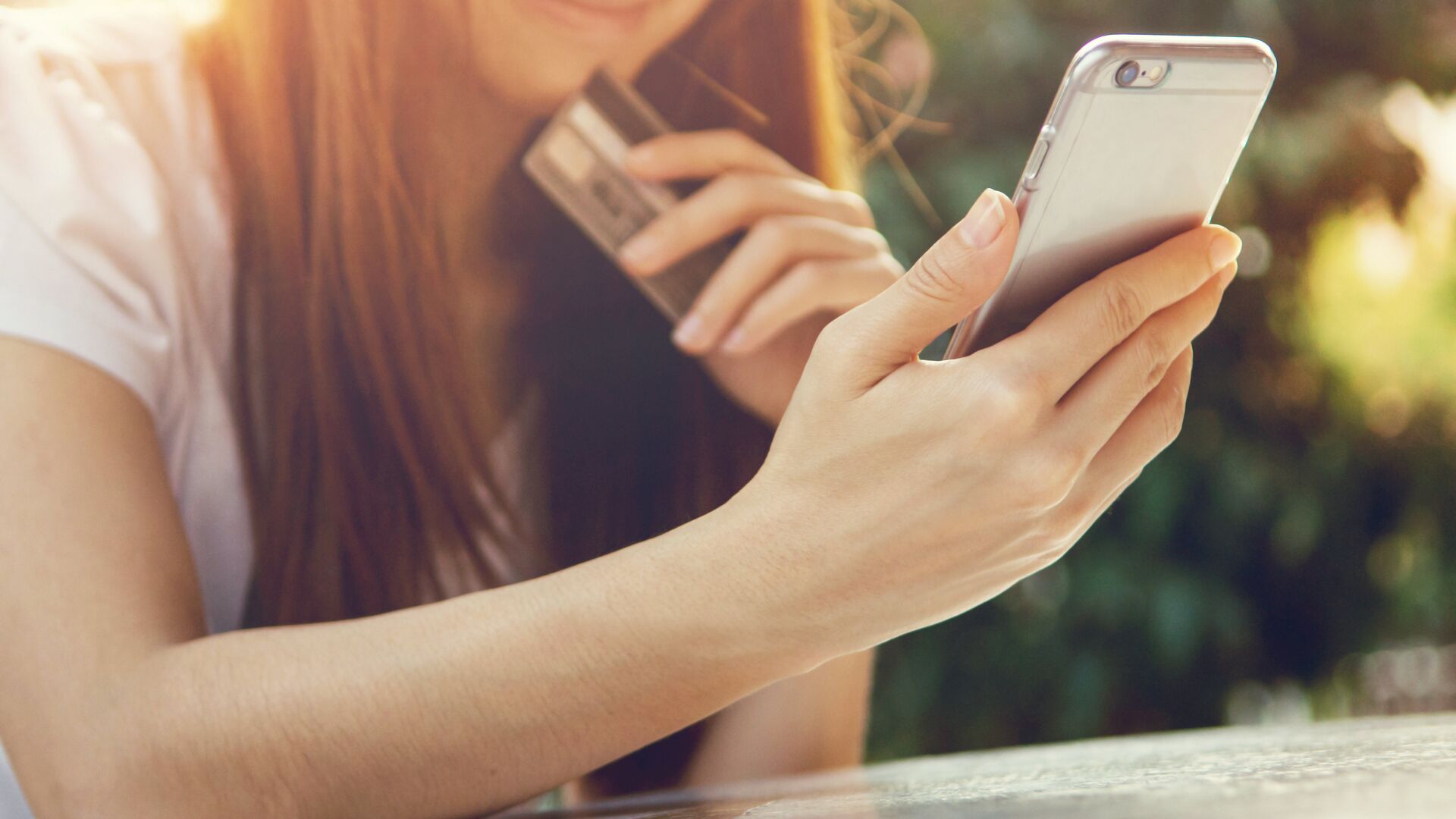 Девушка совершает покупки с помощью мобильного телефона