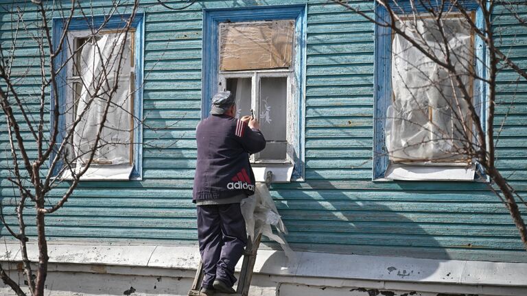 Мужчина заколачивает окна в своем доме в освобожденной Судже
