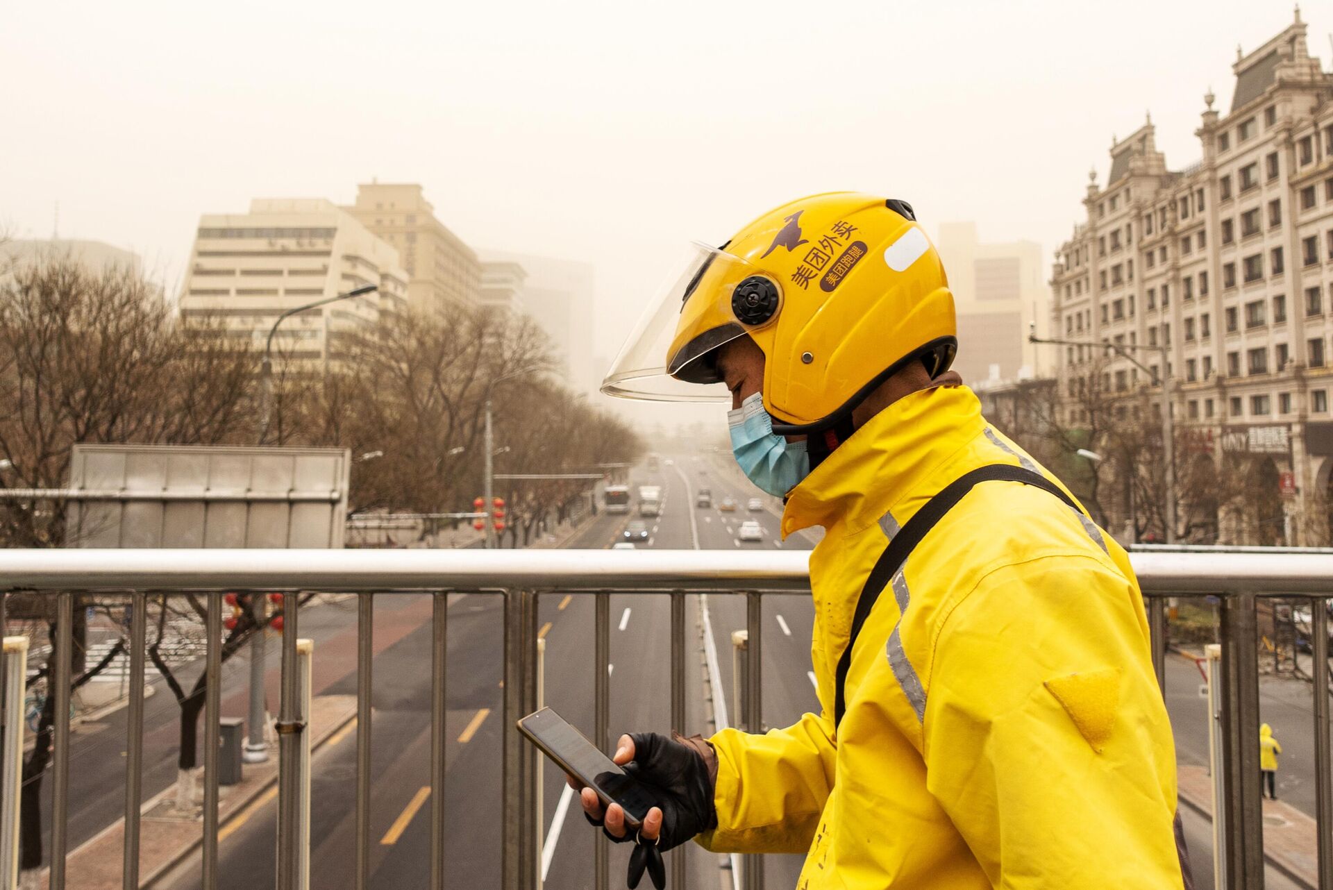 Мужчина на одной из улиц Пекина во время песчаной бури