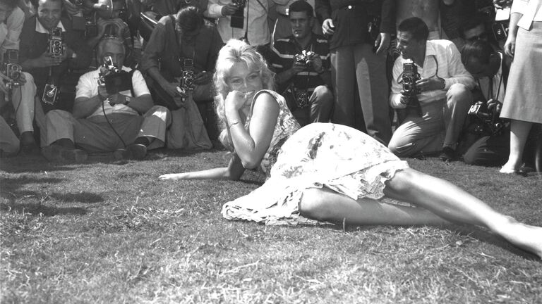 Французская актриса Брижит Бардо позирует для фотографов на лужайке в саду отеля Эксельсиор в Венеции, Италия. 2 сентября 1958